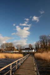 Fototapeta premium Idyllic view from a wooden jetty to the picturesque Sieseby village with old thatched country houses.