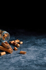 Overturned glass bowl with cinnamon sticks on bluish dark ground. Copy space