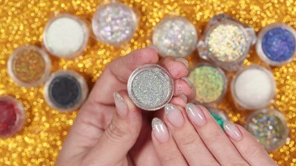 Closeup top view 4k video of female hand holding and showing transparent can with bright silver diamond holographic powder for modern trendy naildesign in professional beauty studio or spa salon. 