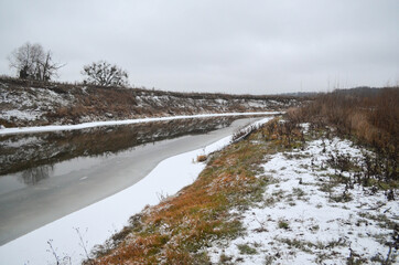 View on the river  in winter.  Grass covered with snow, northern scenery. Wild nature at wintertime.