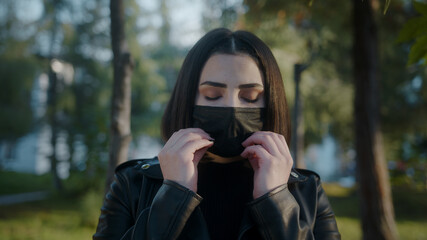 Young woman on the street during pandemic period and she is taking off her black mask and breathing and smiling while looking at camera. Covid-19 concept