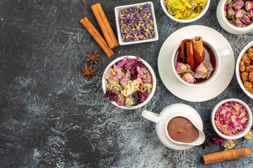 top view of herbal tea with melted chocolate and dry flowers on the left side of grey ground