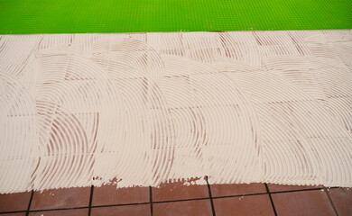 worker applying tile adhesive glue on the floor
