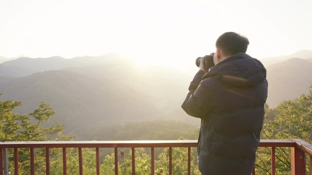 Photographer photographing mountain landscape view in morning at Wat Phrathat Doi Leng viewpoint in Phrae province, Thailand