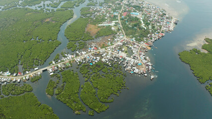 Town in wetlands and mangroves on the ocean coastline from above. Siargao island, Philippines.
