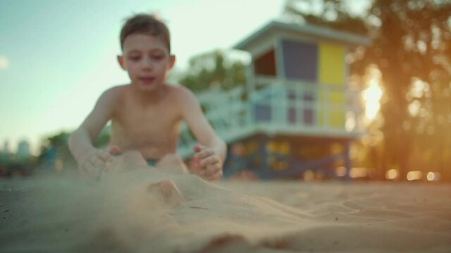 happy kid play with sand and buried on beach or sea shore in summer vacation