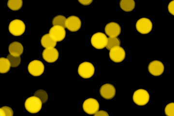 Bright illuminating yellow and golden glitter lights background. Defocused.