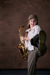 Naklejka na ściany i meble girl plays jazz saxophone. talented child artist musician in a hat, shirt and trousers