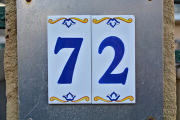 Fototapeta premium A blue house number plaque, showing the number seventy two (72)