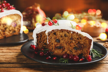 Traditional classic Christmas cake decorated with cranberries, pomegranate seeds and rosemary on wooden table