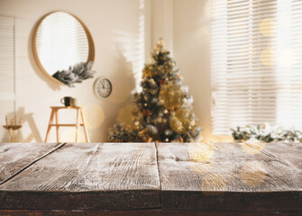 Empty wooden surface and blurred Christmas tree in room on background, bokeh effect. Space for design
