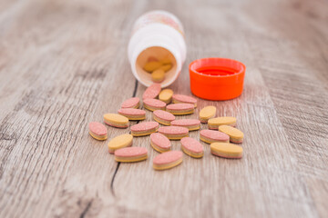 Colored vitamins in the form of tablets and a jar. Wooden background.