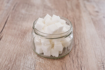 sugar cubes in a jar on a wooden background. Side view.