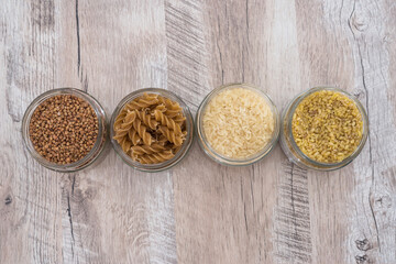 buckwheat, rice, pasta and bulgur in jars on a wooden background.