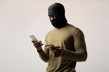 hacker with mobile phone and credit card in hand