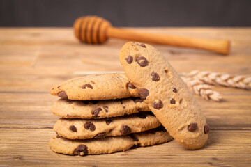 Large image of chocolate chip cookies on a wooden table, dark background.