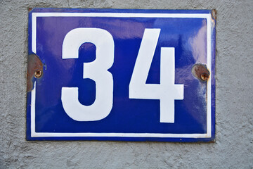 A blue house number plaque, showing the number thirty four (34)