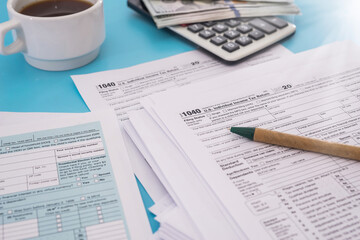 Fototapeta premium Tax concept. US tax form with calculator, pen and dollars on blue background. 1040 form for filling in April.
