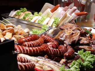 Grilling sausages on the grill. Frying food on charcoal and on fire. Fatty food. Calories and energy for muscles. Picnic on the street. Eating al fresco. Camp Kitchen. German sausages.