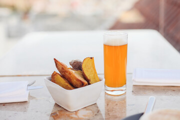 A glass of  beer with fried potatoes on a rooftop terrace