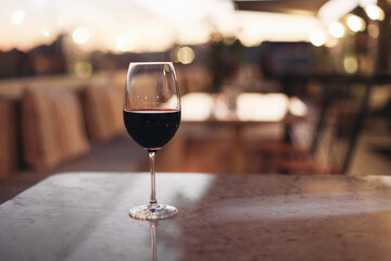 A glass of red wine in a restaurant, evening lights, sunset 
