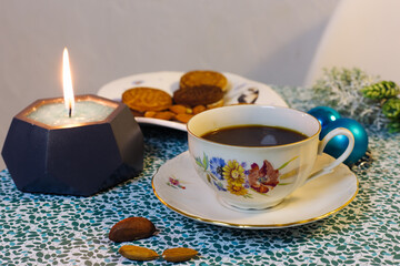 Obraz na płótnie Canvas Cup of coffee, candle, cookies and Christmas decorations on a blue background