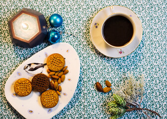 Cup of coffee, candle, cookies and Christmas decorations on a blue background