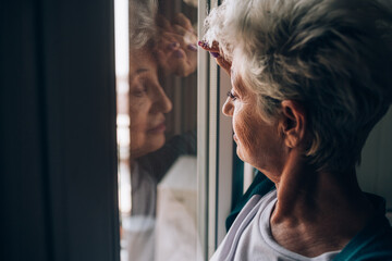 Senior woman looking through apartment window