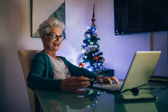 Woman on laptop video call, Christmas tree in background
