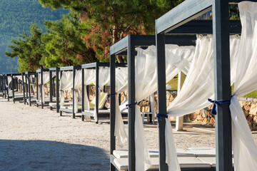 A place to relax on the beach of a Turkish resort. Sun beds with a canopy and a thin transparent...
