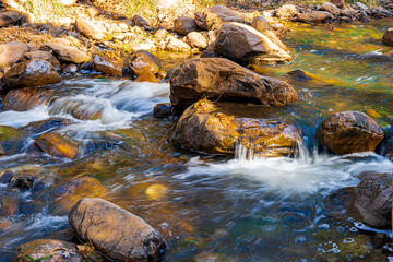 Fototapeta na wymiar Water tumbling over the boulders