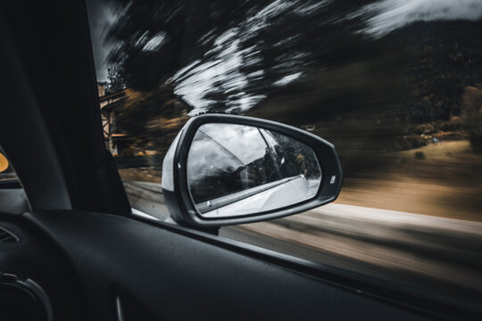 Side-view mirror reflection of moving car