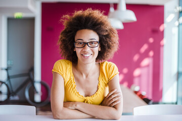 Young woman working in modern office, looking at camera