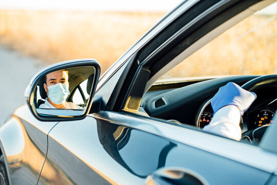 Reflection of man wearing protective mask on side-view mirror