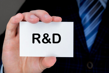 Close-up of man's hand holding and showing visiting card with RESEARCH and DEVELOPMENT word on it.