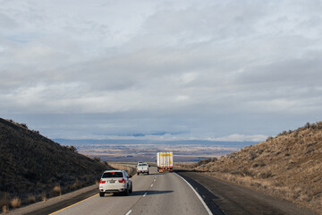 A beautiful landscape with a highway along which cars and trucks drive, on a sunny autumn day among the mountains, a blue sky with fluffy gray-blue clouds. Oregon, USA, 12-5-2019