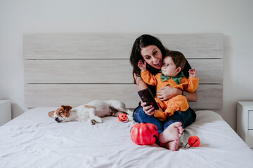 Mother text messaging on smart phone while son sitting on her lap at home