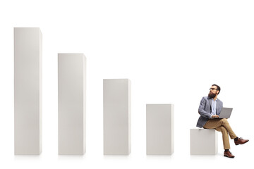 Professional man with a laptop sitting on a column and looking at rising column bars