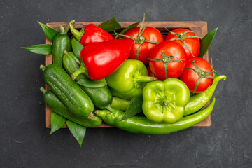 Above view of fresh vegetables in a brown wooden basket on dark background
