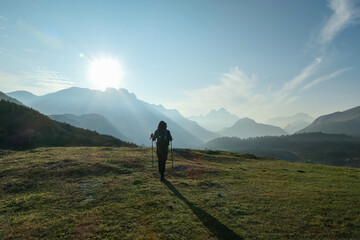 A man enjoying an early morning in Italian Dolomites. The valley below is shrouded in morning haze. In the back there are high mountain chains. Sun slowly rising above the peaks. Golden hour
