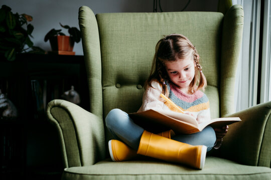 Girl doing homework while sitting on chair at home