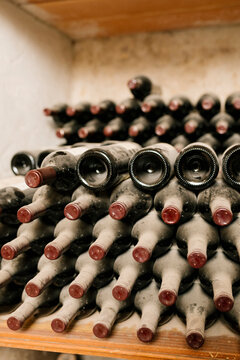 Stack of old wine bottles with dust at cellar