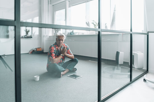 Businessman sitting in prayer position on floor at office