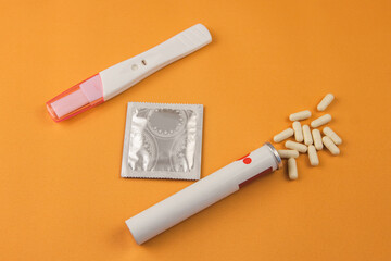 Birth control pills, a condom, and a negative pregnancy test on a yellow background