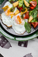 Fried eggs with fresh vegetable salad and microgreens. Dinner table setting. Healthy eating.