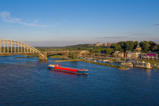 Netherlands, Gelderland, Nijmegen, Aerial view of container ship sailing past bridge on river Waal