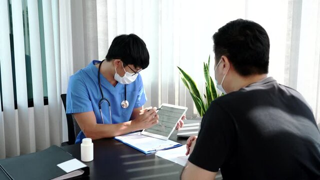 Asian man doctor wear protection face mask during coronavirus and flu outbreak is taking care examining sick patient in hospital.