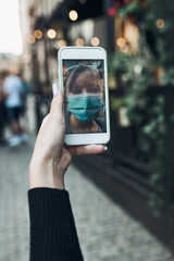 Young woman having video call talking while walking downtown wearing the face mask to avoid virus infection and to prevent the spread of disease in time of coronavirus