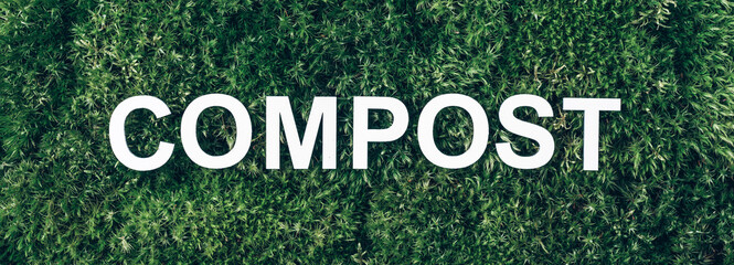 Word Compost on moss, green grass background. Top view. Banner. Biophilia concept. Reduce food waste. Organic waste, composting waste for recycling. Environmentally responsible behavior concept
