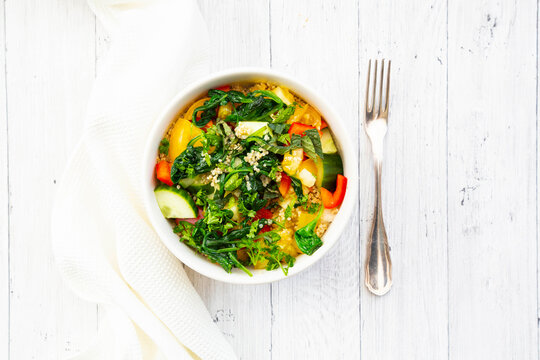 Bowl of warm veganÔøΩquinoaÔøΩsalad with spinach, bell pepper, cucumbers, tomatoes, parsley and mint